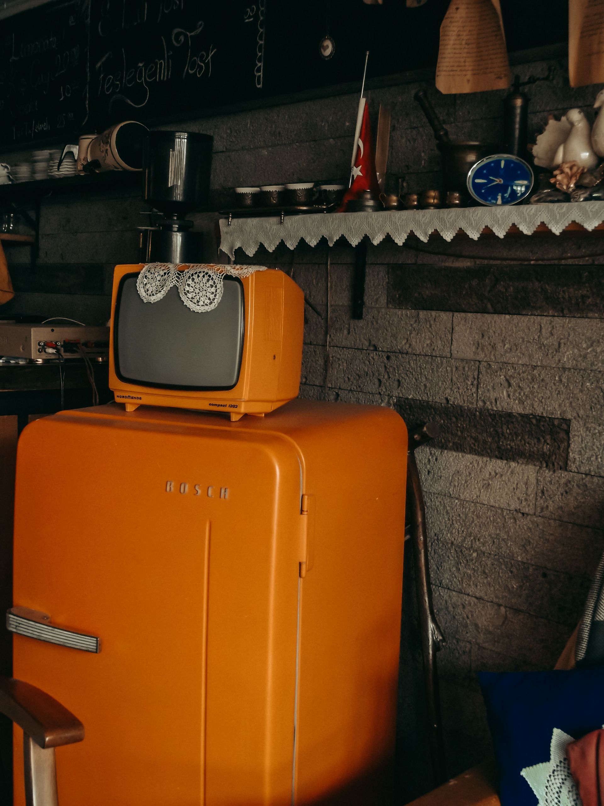 Vintage kitchen scene featuring an orange fridge and retro television set.